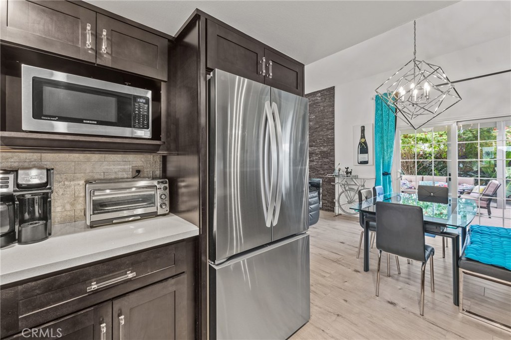 12720 Newport Avenue, Unit 18 Tustin, CA 92780 - Photo 11 of 37 a kitchen with stainless steel appliances a refrigerator a stove a microwave and dining table