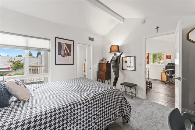 a bedroom with a large bed and a lamp on dresser