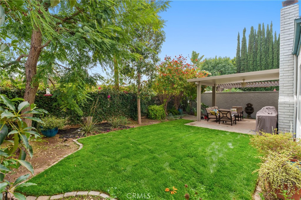 12720 Newport Avenue, Unit 18 Tustin, CA 92780 - Photo 28 of 37 a view of a patio with table and chairs potted plants and large tree