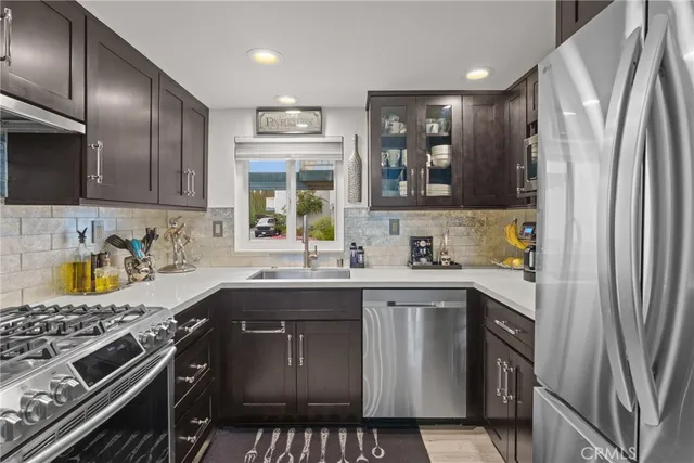 a kitchen with stainless steel appliances granite countertop a sink stove refrigerator and cabinets