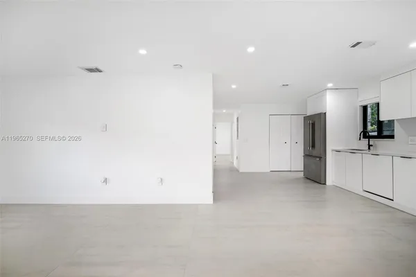 a view of a kitchen with a refrigerator and white cabinets