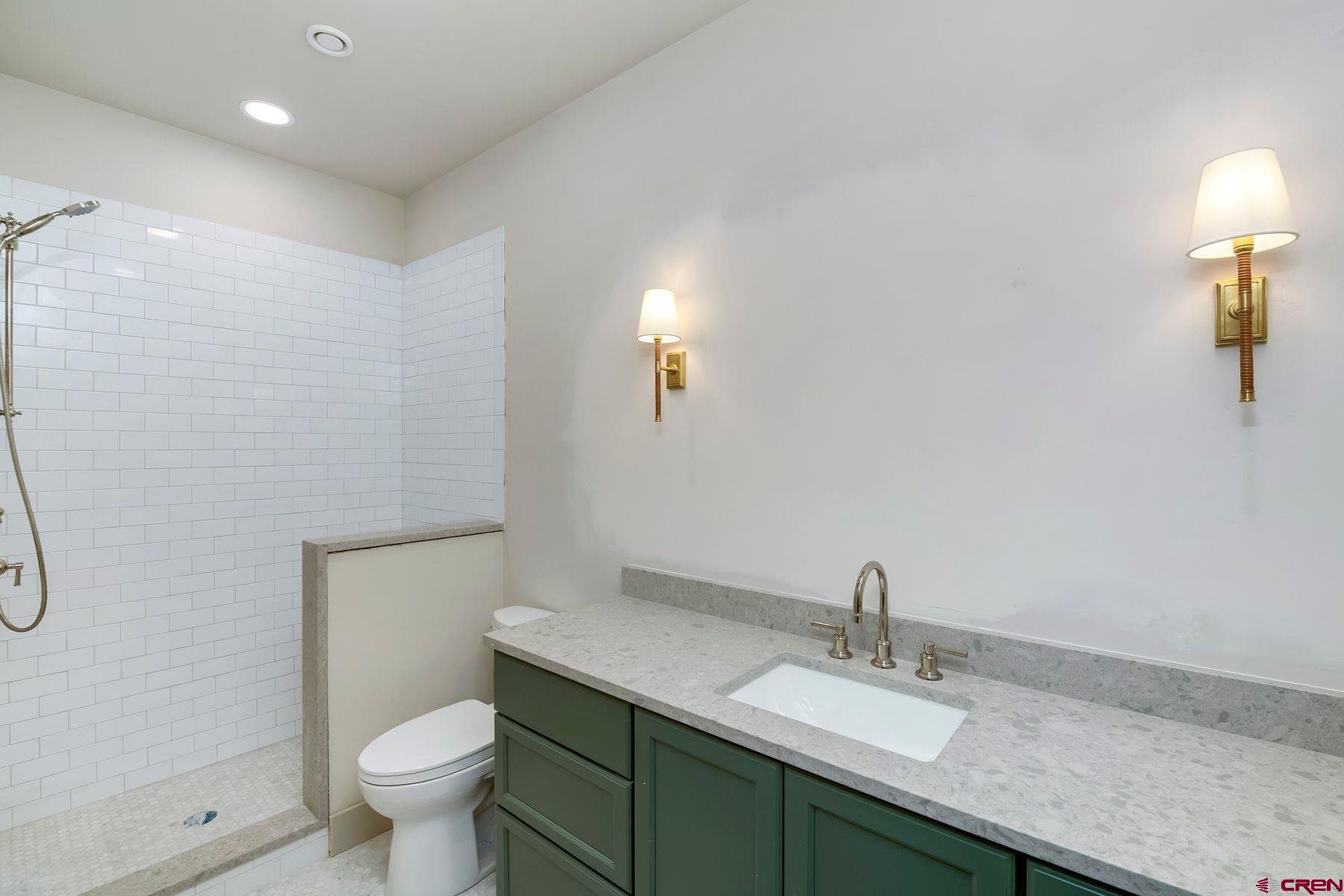 180 Elk Valley Road, Unit 108 Crested Butte, CO 81224 - Photo 15 of 28 a bathroom with a granite countertop sink a toilet and a mirror