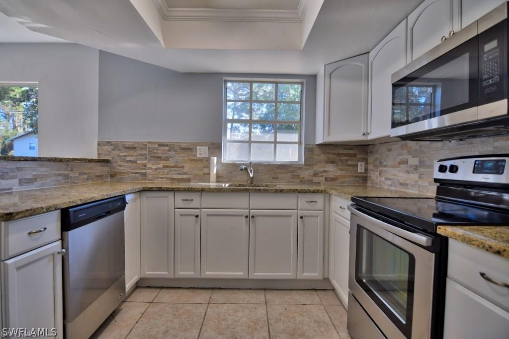 8128 Anhinga Road Fort Myers, FL 33967 - Photo 4 of 12 a kitchen with granite countertop stainless steel appliances white cabinets granite counter tops and a window