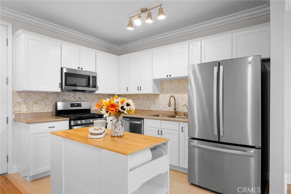 6938 Laurel Canyon Boulevard, Unit 101 North Hollywood, CA 91605 - Photo 12 of 32 a kitchen with stainless steel appliances granite countertop a refrigerator stove microwave and sink
