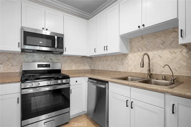 a kitchen with white cabinets and stainless steel appliances
