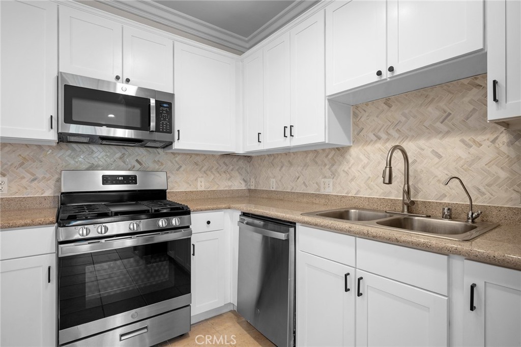 6938 Laurel Canyon Boulevard, Unit 101 North Hollywood, CA 91605 - Photo 14 of 32 a kitchen with white cabinets and stainless steel appliances