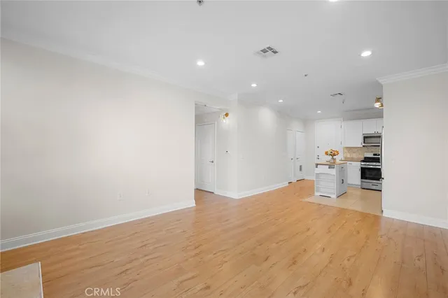 a view of a kitchen with kitchen island wooden floors wooden cabinets and living room