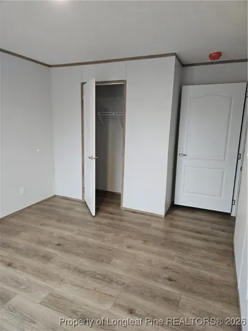 a view of an empty room with wooden floor and cabinet