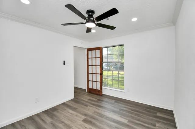 an empty room with wooden floor fan and windows