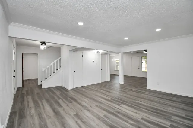 a view of an empty room with wooden floor and a ceiling fan