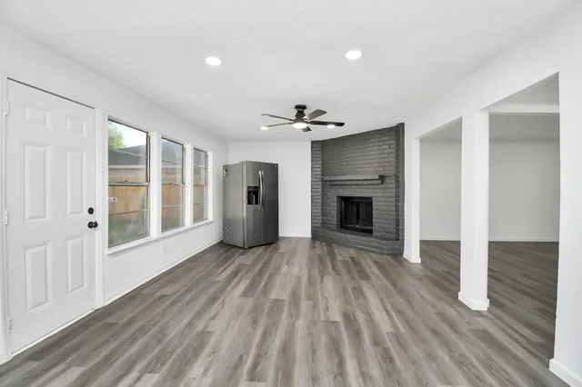 a view of an empty room with wooden floor fireplace and a window