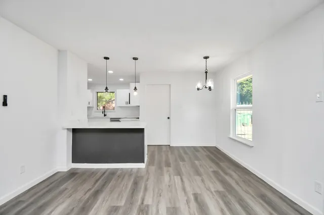 a view of an empty room with window and wooden floor