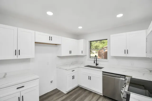 a kitchen with granite countertop white cabinets white appliances and a sink