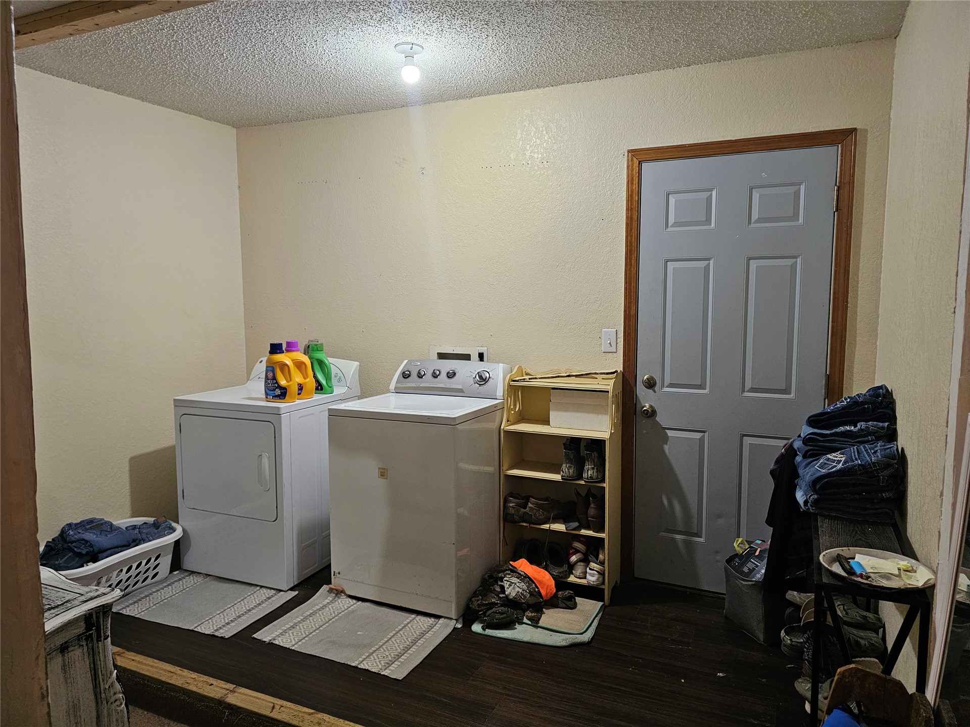 106441 South 4163rd Road Checotah, OK 74426 - Photo 9 of 17 Laundry area featuring dark wood-finish flooring, light-toned walls, and a paneled door with wood trim