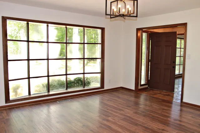 an empty room with wooden floor and windows