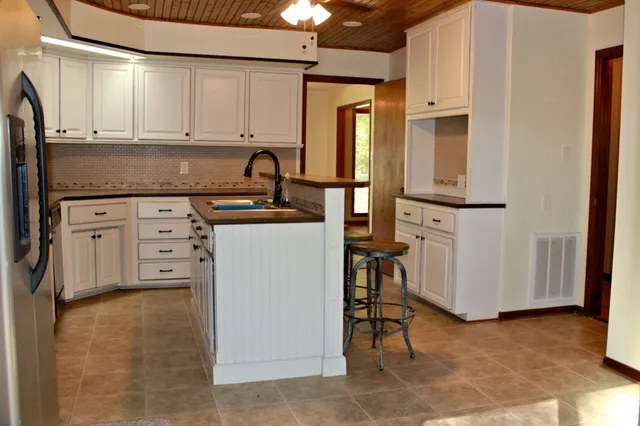 a kitchen with stainless steel appliances granite countertop a refrigerator a stove and white cabinets
