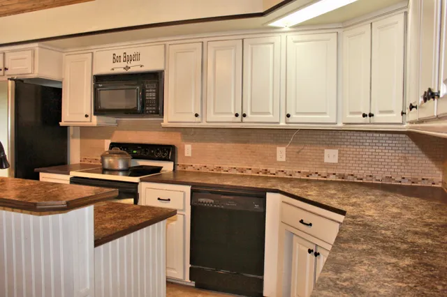a kitchen with stainless steel appliances granite countertop a stove a sink and a microwave