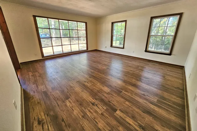a view of an empty room with wooden floor and windows