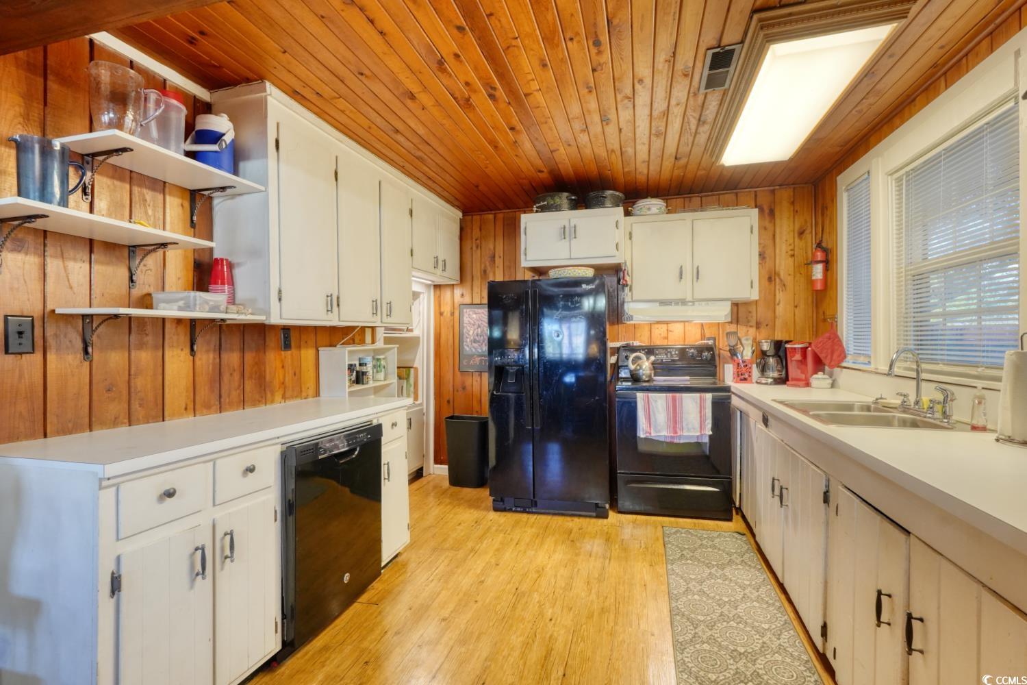 350 Underwood Drive Murrells Inlet, SC 29576 - Photo 12 of 36 Kitchen featuring wood walls, open shelves, black appliances, light countertops, and light wood-type flooring