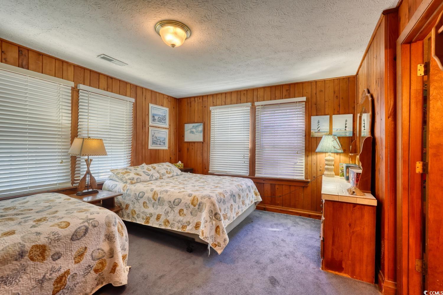 350 Underwood Drive Murrells Inlet, SC 29576 - Photo 28 of 36 Bedroom featuring dark colored carpet, wooden walls, and a textured ceiling
