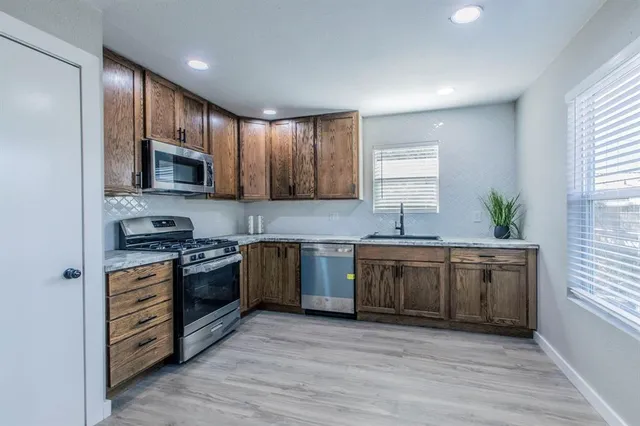 a large kitchen with stainless steel appliances granite countertop a stove a sink and a microwave