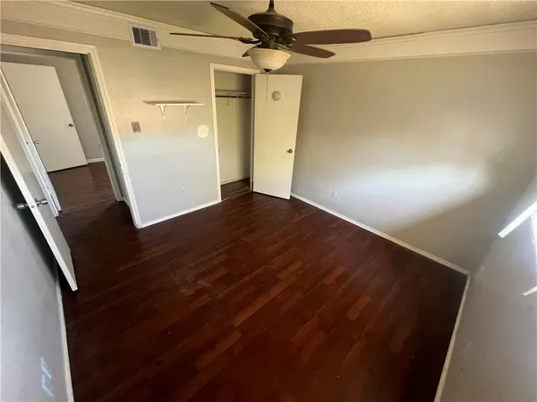 en empty room with wooden floor and fan