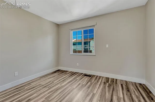 a view of an empty room with wooden floor and a bathroom