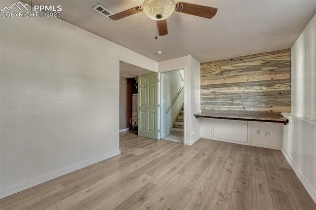 a view of a livingroom with wooden floor stairs and a ceiling fan
