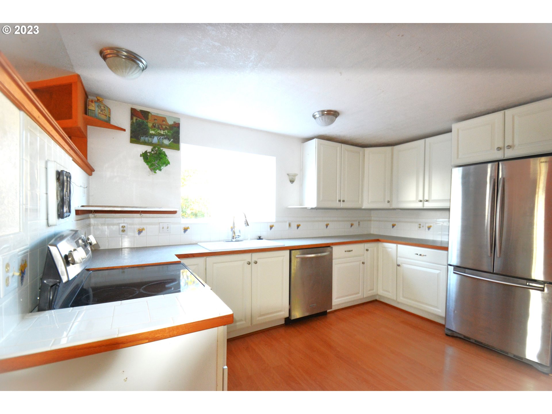 1985 Roseburg Road Myrtle Point, OR 97458 - Photo 6 of 29 a kitchen with a sink dishwasher a refrigerator and white cabinets with wooden floor