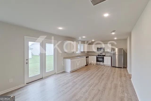 a kitchen with stainless steel appliances granite countertop a lot of cabinets and wooden floor