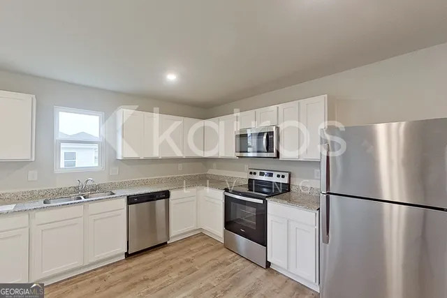 a kitchen with a refrigerator a sink dishwasher a stove and white cabinets with wooden floor