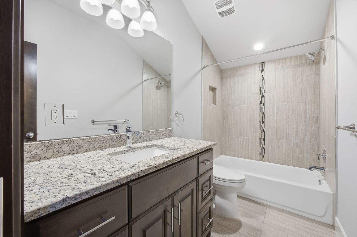 1125 Walton Lane, Unit D Austin, TX 78721 - Photo 27 of 34 a bathroom with a granite countertop sink a toilet and bathtub