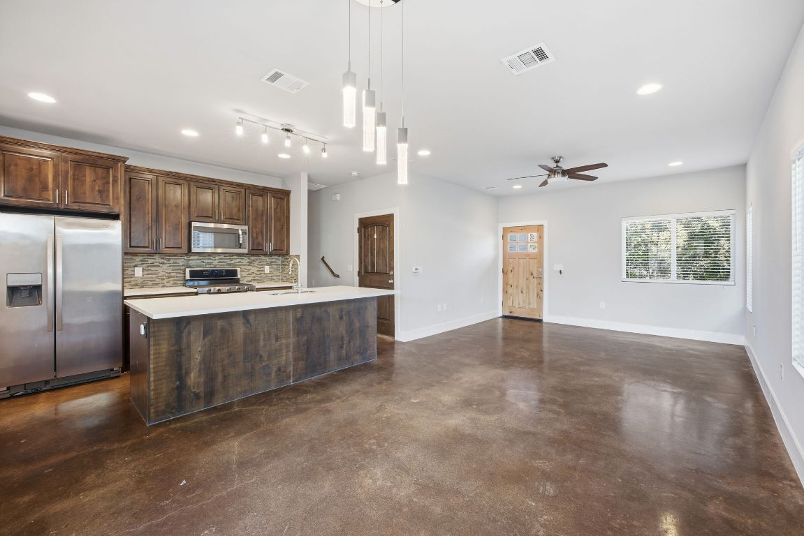 1125 Walton Lane, Unit D Austin, TX 78721 - Photo 8 of 34 a kitchen with stainless steel appliances kitchen island granite countertop a refrigerator oven a sink dishwasher with a dining table and chairs