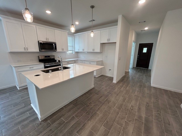 26711 Grandiflora Drive Magnolia, TX 77355 - Photo 3 of 19 a kitchen with stainless steel appliances a stove a refrigerator a sink a microwave oven and white cabinets with wooden floor