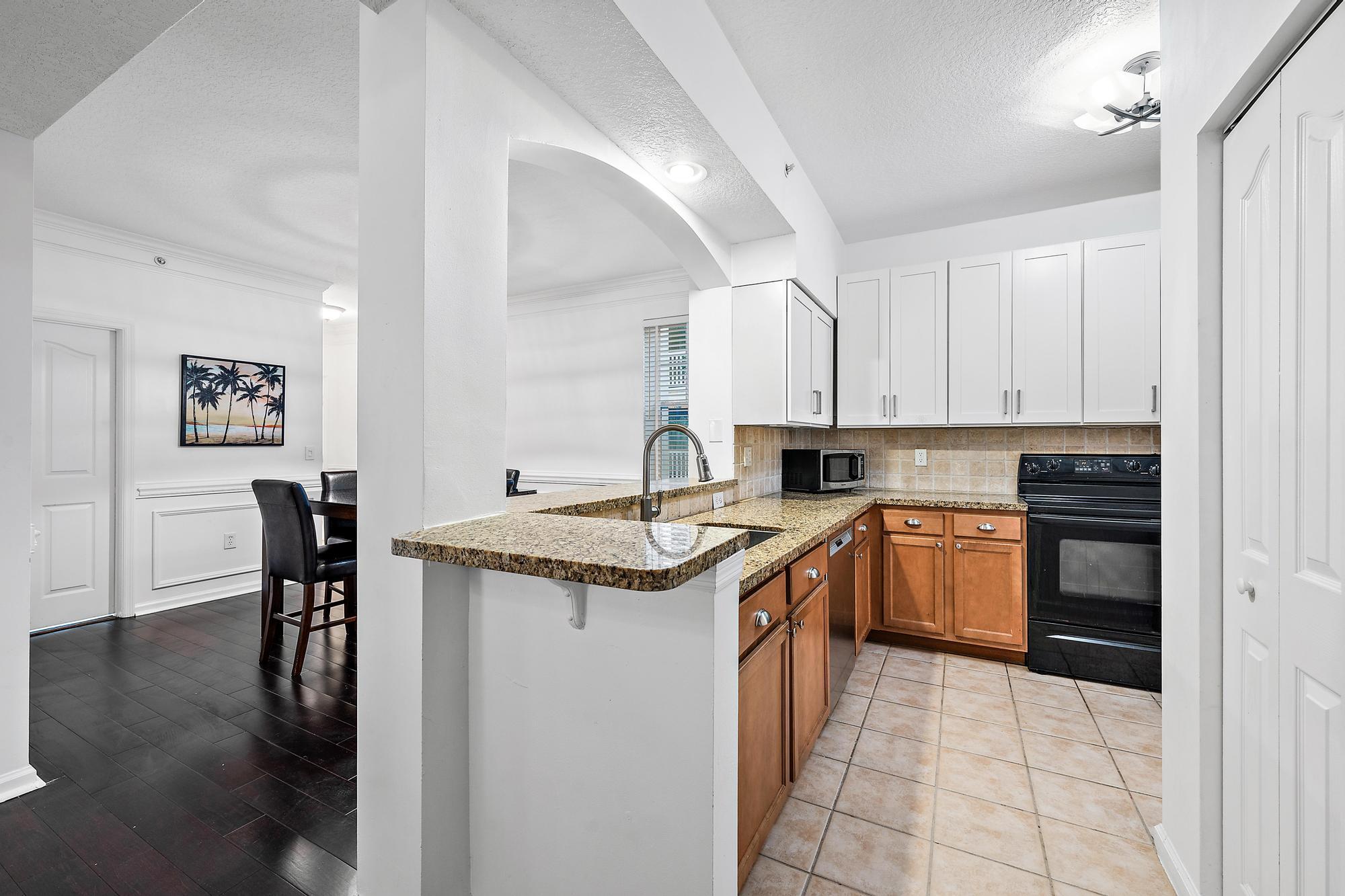 225 Murcia Drive, Unit 201 Jupiter, FL 33458 - Photo 13 of 42 a kitchen with stainless steel appliances granite countertop a stove top oven a sink a dining table and chairs