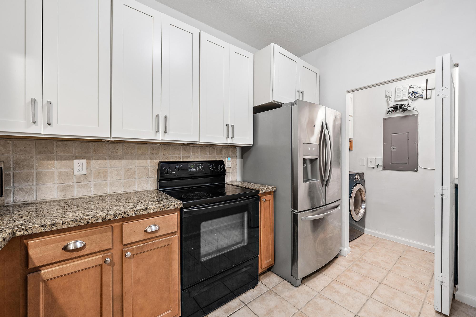 225 Murcia Drive, Unit 201 Jupiter, FL 33458 - Photo 17 of 42 a kitchen with stainless steel appliances granite countertop a refrigerator a stove a microwave and cabinets