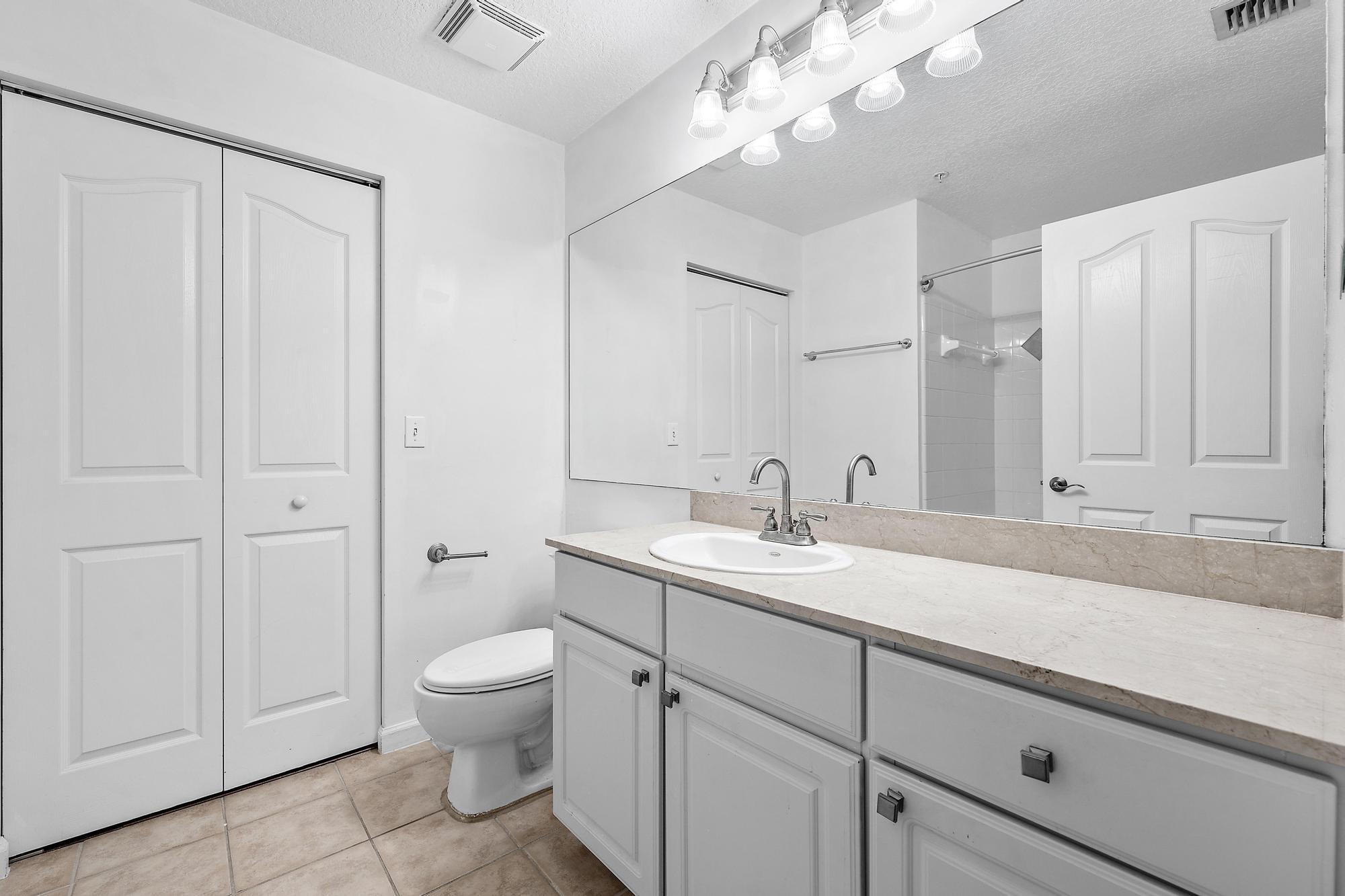 225 Murcia Drive, Unit 201 Jupiter, FL 33458 - Photo 23 of 42 a bathroom with a granite countertop sink a toilet and a mirror
