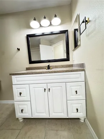 a view of an empty room with wooden floor and fan