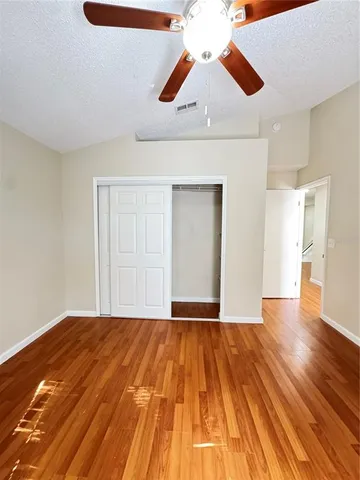 an empty room with wooden floor fan and windows