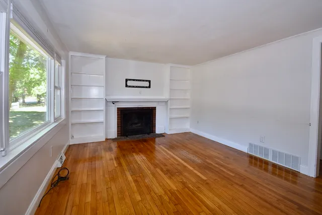 a view of empty room with wooden floor and fireplace