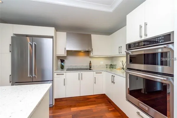 a kitchen with granite countertop a refrigerator and a stove top oven