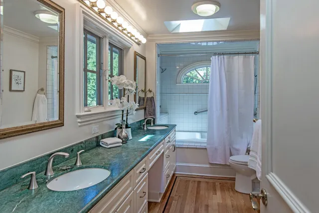 a bathroom with a granite countertop sink a toilet a mirror and shower