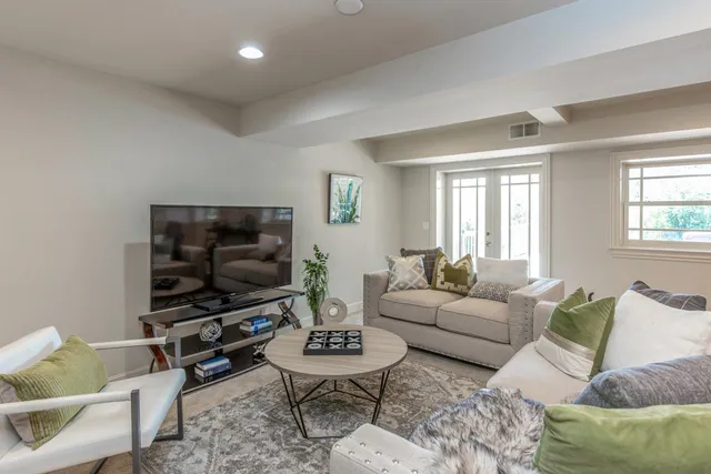 a living room with furniture a flat screen tv and a window