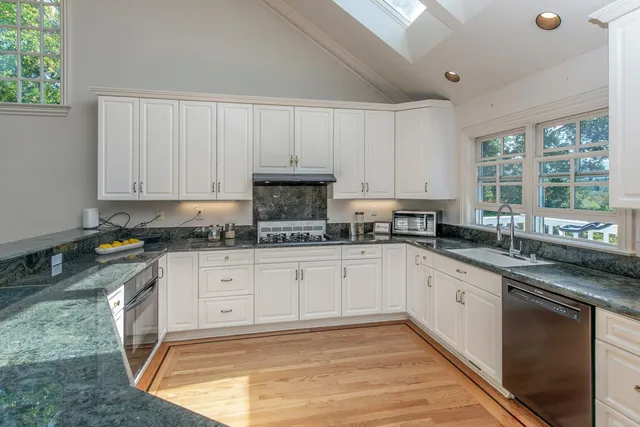 a kitchen with stainless steel appliances granite countertop a stove a sink and white cabinets
