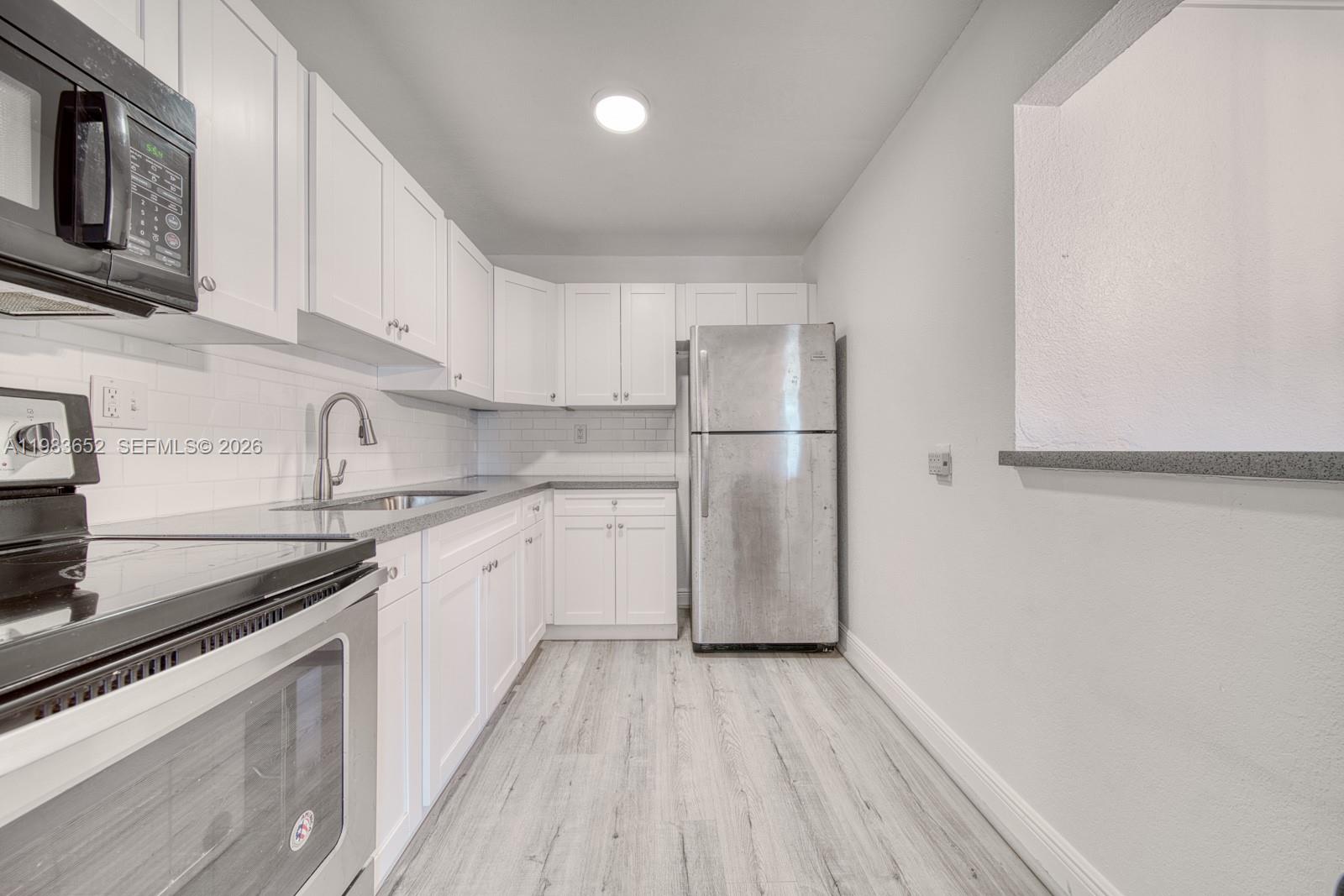 9459 Southwest 76th Street, Unit R5 Miami, FL 33173 - Photo 7 of 33 a kitchen with a sink a refrigerator and cabinets