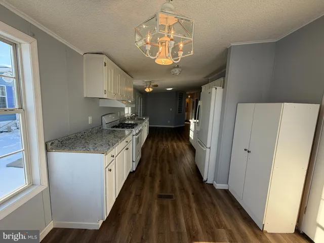 a kitchen with stainless steel appliances granite countertop a refrigerator a sink dishwasher a stove and a dining table with wooden floor