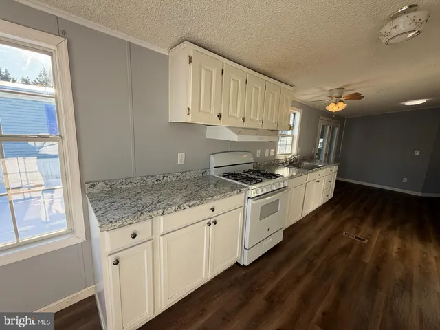 a kitchen with granite countertop white cabinets and white appliances