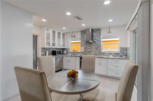 a kitchen with stainless steel appliances granite countertop a sink a stove a dining table and chairs