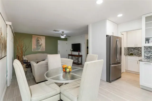 a living room with furniture a flat screen tv and a refrigerator