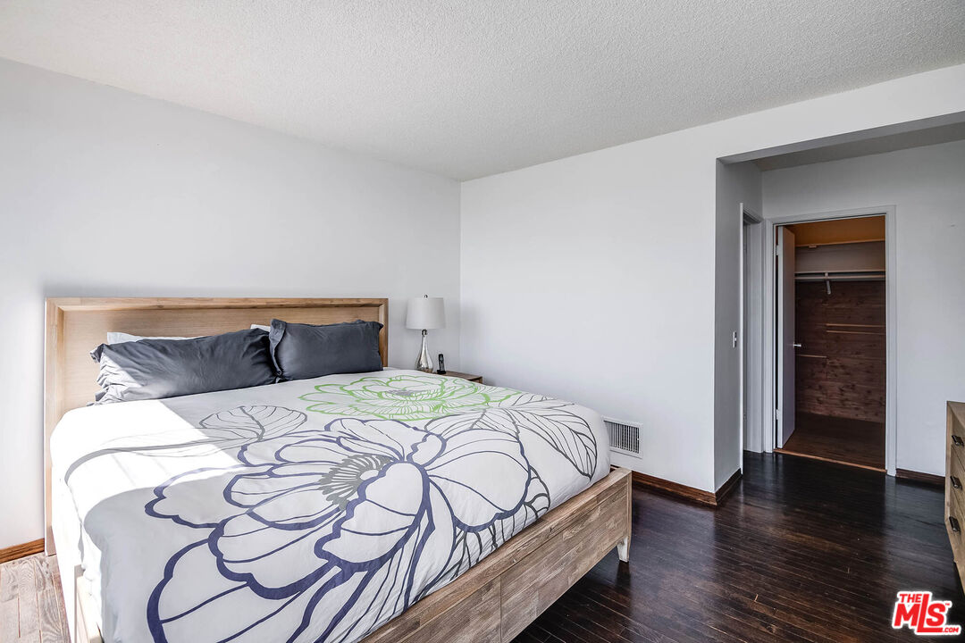 3557 Serra Road Malibu, CA 90265 - Photo 26 of 32 a bedroom with a bed and wooden floor